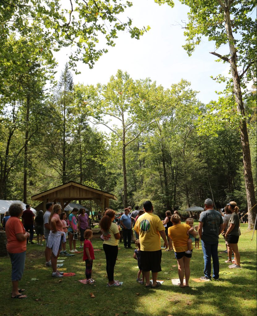Festival goears participating in a cake walk as the summer sun peaking through the trees.